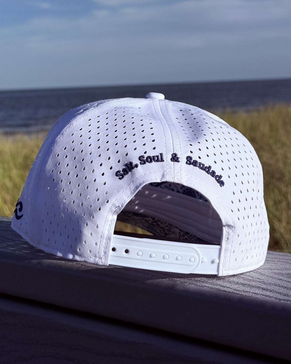 The back of the white snapback, Salt, Soul and Saudade embroidered in navy.