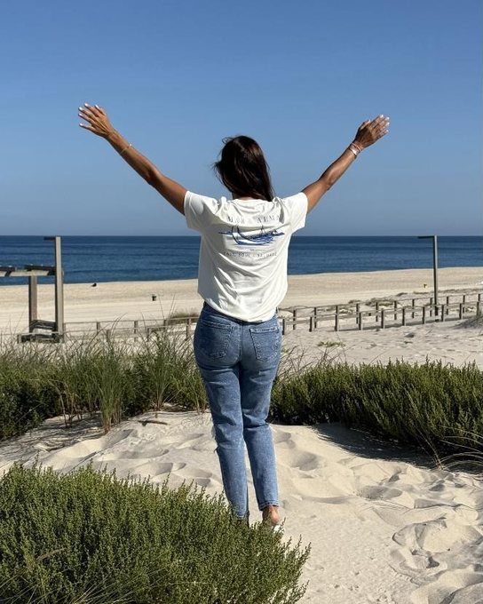 The Founders Tee worn on the dunes, arms raised, facing the Atlantic.