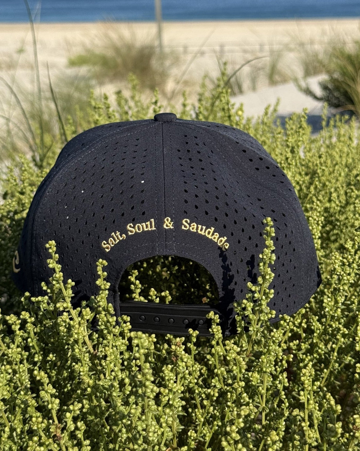 The back of the navy snapback, Salt, Soul and Saudade embroidered in gold.