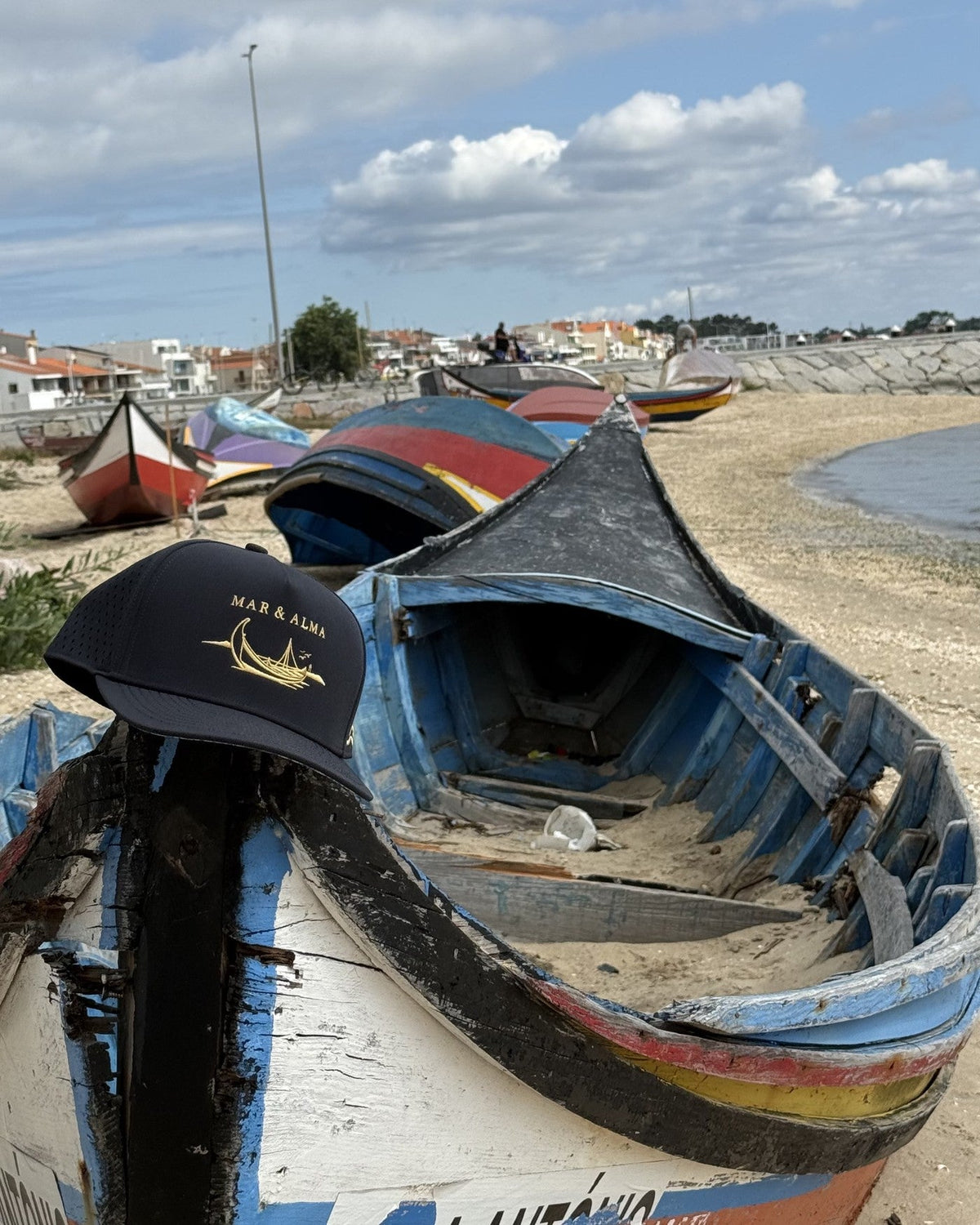 The navy snapback resting on the prow of a beached moliceiro.