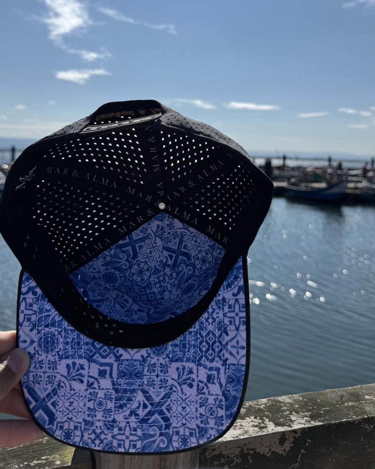 The navy snapback held up to show the azulejo tile lining under the brim.