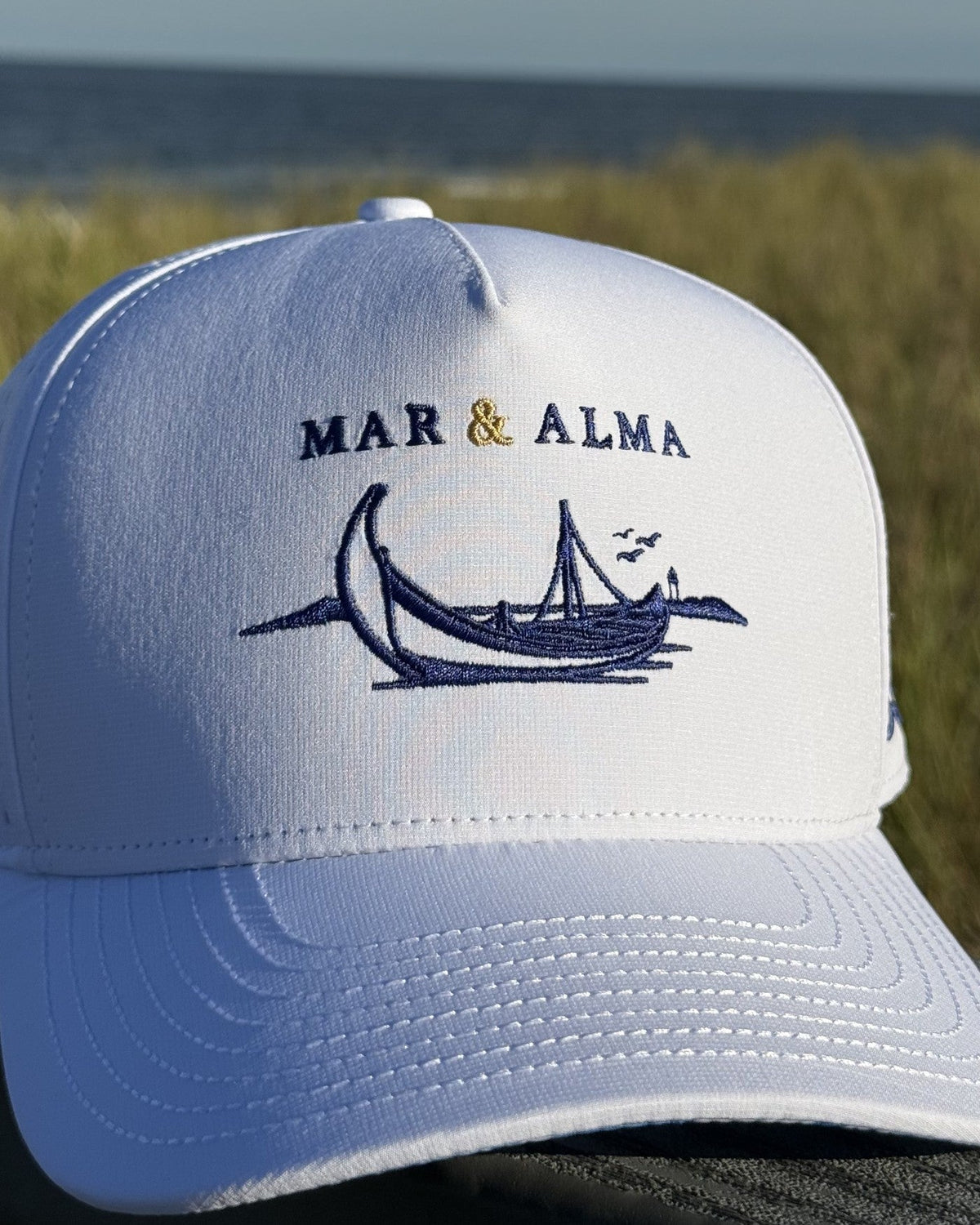 The Heritage Moliceiro Snapback in white, the moliceiro in navy under a gold wordmark.