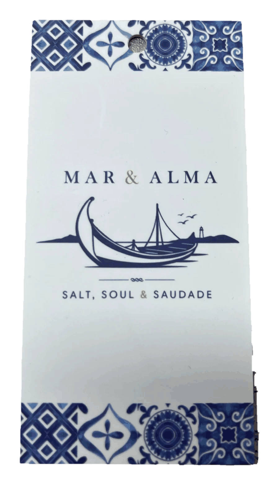 The printed Mar & Alma hangtag: a white card with azulejo tile bands top and bottom, the moliceiro mark and wordmark centred between them.